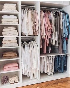 an organized closet filled with clothes and folded linens on shelving unit shelves in front of hardwood flooring