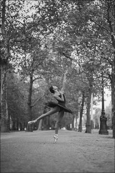 black and white photograph of a ballerina in the middle of a park with trees