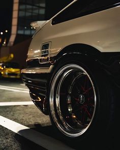 a white car parked in front of a tall building at night with its lights on