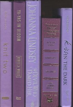 a row of purple books sitting on top of a shelf