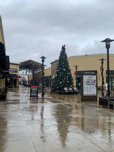 there is a christmas tree in the middle of this shopping center street with lights on it