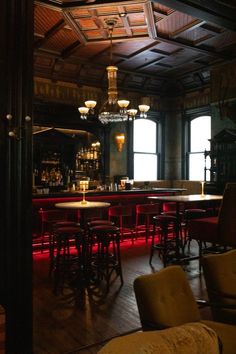 a dimly lit bar with lots of stools and tables in front of the bar