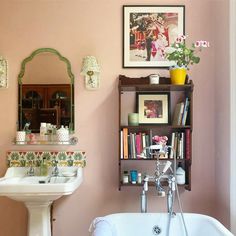 a bathroom with pink walls and a white bathtub next to a sink under a mirror