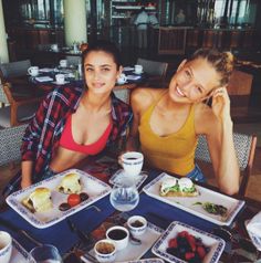 two women sitting at a table with plates of food