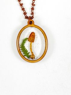 a necklace with an image of a mushroom and fern