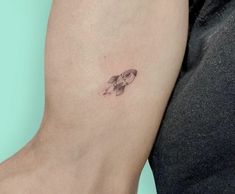 a small fish tattoo on the left side of the right arm, with an arrow in it's center