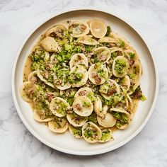 pasta with broccoli and shells in a white bowl on a marble countertop