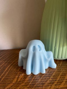 a small plastic elephant sitting on top of a wooden table next to a green vase