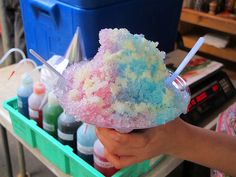 a person holding an ice cream sundae in their hand with other items behind it