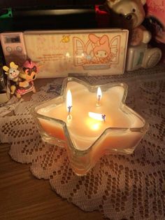 two lit candles sitting on top of a doily next to a teddy bear and other toys