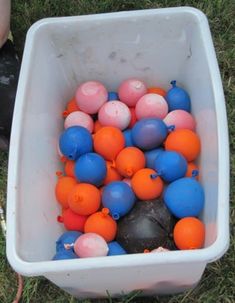 a white bucket filled with balls on top of grass