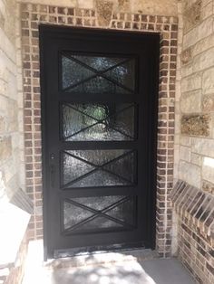 a black front door on a brick building with glass inserting the top and bottom