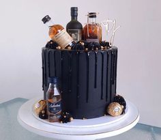 a black cake with liquor bottles on top and decorations around the edges, sitting on a white plate