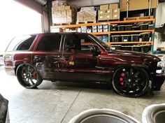 a maroon truck parked in a garage next to some shelves with boxes on the wall