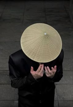 a man with a hat on his head and hands in front of him, looking down at the ground