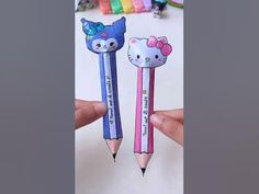 two pencils with hello kitty on them are being held by someone's hand