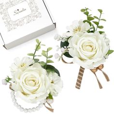 two white flowers are sitting next to each other in front of a box with ribbon