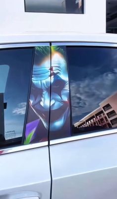 the back window of a white car with an image of a clown painted on it