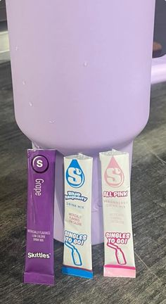 three different types of toothpaste sitting in front of a purple container on the floor