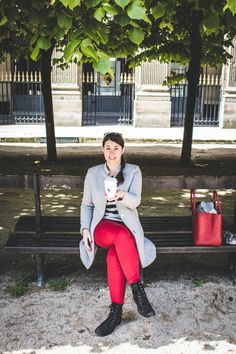 a woman sitting on a park bench holding a cup