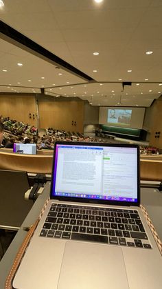 an open laptop computer sitting on top of a table in front of a lecture hall