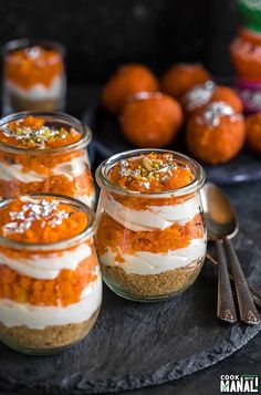 small jars filled with food sitting on top of a black table next to spoons