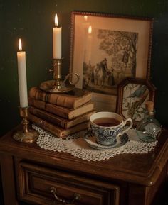 a table topped with books and a cup filled with tea next to a candle holder