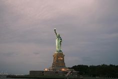 the statue of liberty is lit up on a cloudy day in new york city, ny