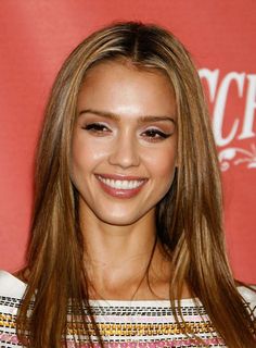 a woman with long brown hair smiling at the camera