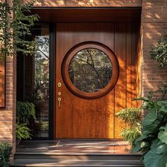 a wooden door with a circular window in the middle and plants around it on either side