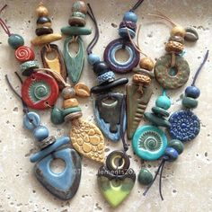 a collection of different colored beads and pendants on a white surface with holes in the middle