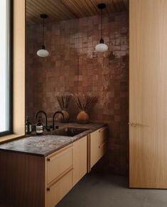 a kitchen with wooden cabinets and marble counter tops in front of an open door that leads to the outside