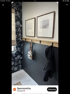 a bathroom with two pictures hanging on the wall and a coat rack in front of it