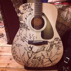 an acoustic guitar sitting on top of a wooden table