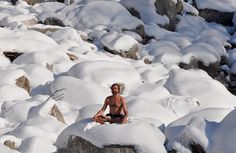 a man sitting on top of snow covered rocks