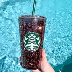 a hand holding a starbucks drink in front of a swimming pool