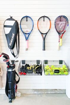 four tennis rackets hanging on the wall in a room with other sports items and equipment