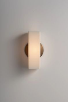 a white wall mounted light on the side of a gray wall with a brown trim