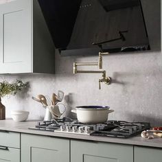 a stove top oven sitting inside of a kitchen next to white cupboards and drawers