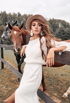 a beautiful young woman standing next to a horse