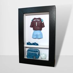 a shadow box with an image of a football jersey and other items in the frame