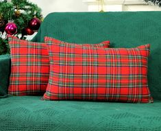 two red and green plaid pillows sitting on top of a couch next to christmas decorations