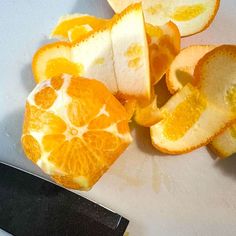 an orange cut in half on a cutting board next to a knife