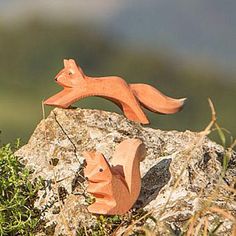 two wooden toy animals sitting on top of a rock