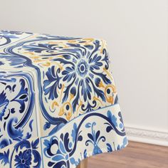 a blue and white table cloth with an ornate design on it, sitting in front of a wood floor