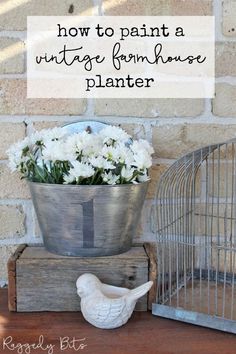 a bird cage with flowers in it next to a planter