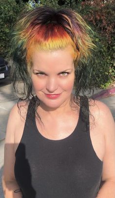 a woman with multicolored hair standing in the street