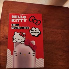 the hello kitty pink humider is on top of a wooden table next to a red box