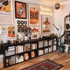 a living room filled with lots of books and posters on the wall next to a wooden floor