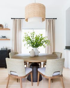 a dining room table with four chairs and a potted plant on top of it